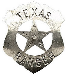 A shield shaped badge with a star in the center. The word "Texas is printed across the top of the badge and the word "Ranger" is printed across the bottom. In the points of the star are the letters that spell "Texas" and in the middle of the star is another much smaller star.