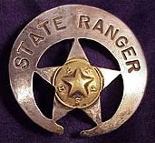 A silver circle star badge with the star closer to the bottom rather than centered. The words "Sate Ranger" are printed at the top and in the middle of the star is a gold star with the letters of the word "Texas" arranged with one letter between two star points.