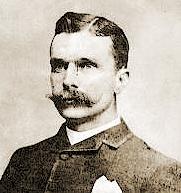 A black and white head shot of a man with a mustache.