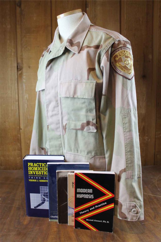 A camouflage uniform shirt with a Texas Ranger patch and four crime scene investigation text books.