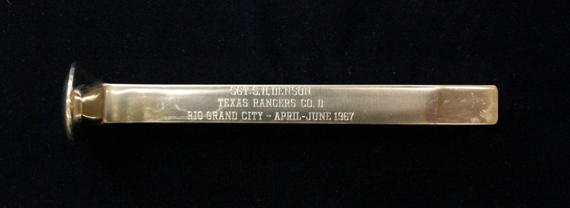 A silver spike with the following words on it "Sgt. S. H. Denson Texas Rangers Co. D Rio Grand City - April - June 1967".