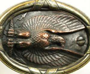 Bronzed metal. Eagle inside circular frame.