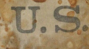 gray letters US on stained brown fabric