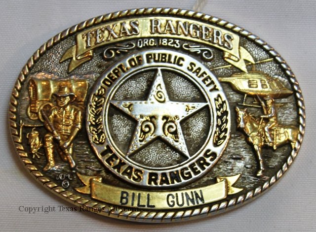 brass, oval belt buckle with badge in the center, a frontier Ranger on the left, and modern Ranger on the right