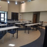 A room with tables and chairs set up like a classroom facing a podium.