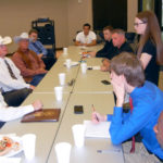 A group of students and adults sitting across from three Texas Rangers.