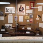 An exhibit with multiple firearms, a US Army poster, helmets, and photographs of World War One.